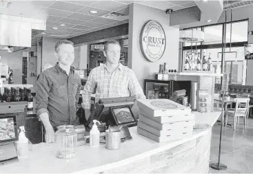  ?? David Hopper photos ?? Crust Pizza owners Mark Rasberry and Clint Price wait for a customer to pick up an order at the new Crust Pizza in the Creekside Park Village Center, This is the third Crust Pizza to open in The Woodlands.