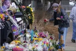  ?? PHOTOS BY DAVID ZALUBOWSKI — THE ASSOCIATED PRESS ?? A mourner places a rose amid bouquets Wednesday in tribute around a police cruiser for Boulder, Colo., police officer Eric Talley in Boulder. Talley was one of 10 victims in Monday’s mass shooting at a King Soopers grocery store.