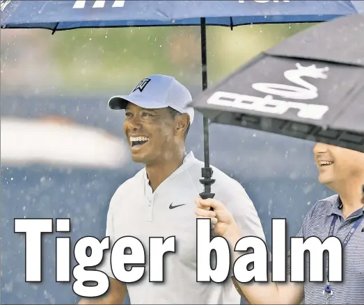  ?? Getty Images ?? RAIN, RAIN ... Tiger Woods takes Tuesday’s storm in stride, though it limited his practice time.