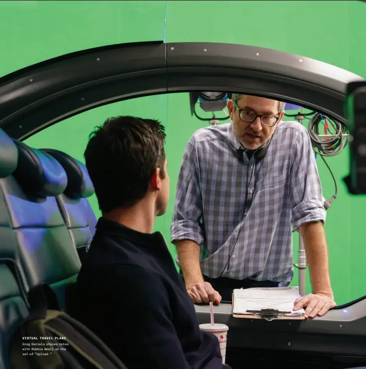  ??  ?? VIRTUAL TRAVEL PLANS Greg Daniels shares notes with Robbie Amell on the set of “Upload.”