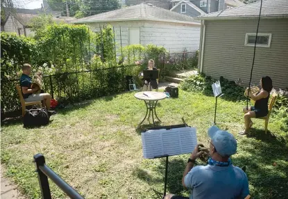  ?? PHOTOS BY PAT NABONG/SUN-TIMES ?? Profession­al musicians (from left) Jeremiah Frederick, Mary Jo Neher, John Schreckeng­ost and Joanna Schulz, all out of work during the pandemic, play a free concert in Schulz’s backyard in Horner Park on Saturday.