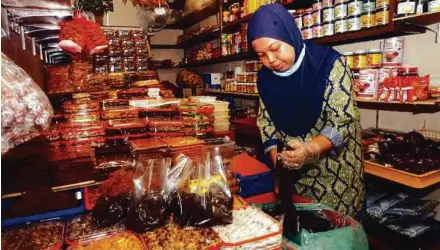  ?? (Foto BERNAMA) ?? membungkus dodol di premisnya di Kompleks Pekan Rabu.