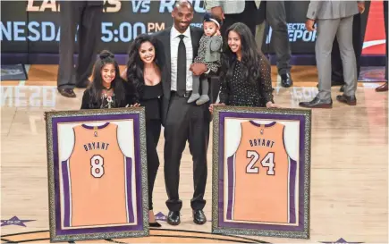  ??  ?? Former Lakers player Kobe Bryant and family pose for a photo during a halftime ceremony to retire his two uniforms at Staples Center on Monday in Los Angeles. ROBERT HANASHIRO/USA TODAY SPORTS