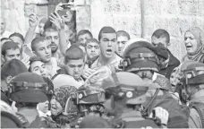  ?? AHMAD GHARABLI, AFP/GETTY IMAGES ?? Palestinia­ns shout Sunday in front of Israeli security forces blocking a road to the Al-Aqsa Mosque in Jerusalem’s Old City.