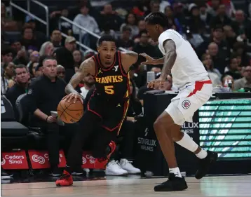  ?? HARRY HOW — GETTY IMAGES ?? Dejounte Murray of the Atlanta Hawks drives to the basket in front of the Clippers' Bones Hyland during Sunday night's game at Crypto.com Arena. The Clippers' spiral continued with a 110-93loss to the sub-.500Hawks.