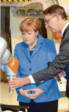  ?? Foto: Silvio Wyszengrad ?? Da waren die Zeiten noch in Ordnung: Ex-Kuka-Chef Reuter zeigte Kanzlerin Merkel im Jahr 2015 Hightech aus Augsburg. Sich statt chinesisch­er Investoren an der Firma zu beteiligen, davor schreckte der Bund aber zurück.