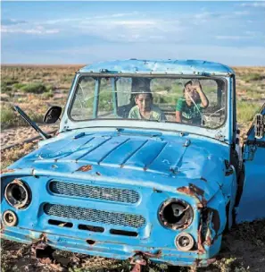  ?? ?? What’s left: a rusting ship sitting in a dried-up area of the aral sea in Muynak, and (right) children playing inside a rusted dilapidate­d car along the dried-up aral sea. — ap