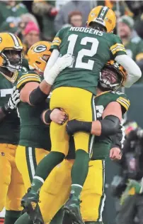  ?? MARK HOFFMAN/MILWAUKEE JOURNAL SENTINEL ?? Aaron Rodgers gets a lift after breaking the Packers’ record for touchdown passes Saturday.