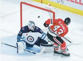  ?? CHRIS SWEDA/CHICAGO TRIBUNE ?? Blackhawks center Colin Blackwell scores a goal on Jets goaltender Connor Hellebuyck in the second period Friday at the United Center.