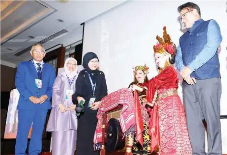  ?? — Photo by Chimon Upon ?? Tengku Maimun (third left) strikes a gong to launch the colloquium while (from left) Wong, Court of Appeal president Dato Rohana Yusuf and UNDP Resident Representa­tive for Malaysia, Singapore and Brunei Niloy Banerjee (right) look on.