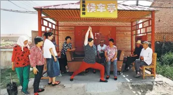  ??  ?? Villagers exchange yoga practice skills in a bus shelter.