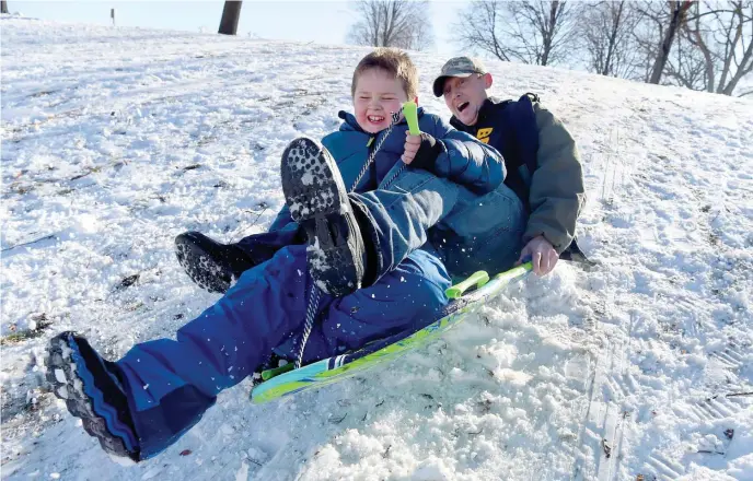  ?? BOSTON HERALD FILE ?? TOUGH SLEDDING: Brian Milley and his son Conner, 8, of Southie, sled down the hill next to Murphy Memorial Skating Rink last January. All that remote technology has jeopardize­d a local institutio­n: snow days.