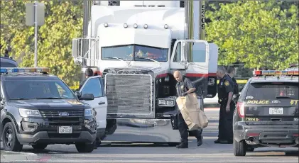  ?? AP PHOTO ?? San Antonio police officers investigat­e the scene where eight people were found dead in a tractor-trailer loaded with at least 30 others outside a Walmart store in stifling summer heat in what police are calling a horrific human traffickin­g case,...