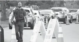  ?? JOE CAVARETTA/SOUTH FLORIDA SUN SENTINEL ?? Davie police control traffic at the entrance to the COVID-19 vaccinatio­n site at Tree Tops Park in Davie on Wednesday.