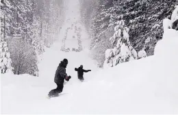  ?? RYAN HOFFMAN/THE TAHOE TRIBUNE ?? Two men snowboard down a steep street in South Lake Tahoe, Calif., on Friday, after heavy snowfall.