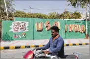  ?? AJIT SOLANKI / AP ?? A man rides past a wall painted with portraits of President Donald Trump and Indian Prime Minister Narendra Modi in Ahmadabad, India, on Tuesday.