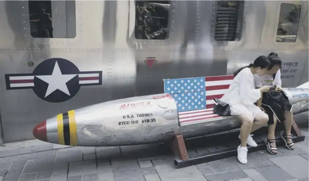  ?? PICTURE; AP ?? Chinese women sit on a rocket shaped bench with an American flag used as a marketing gimmick for a US clothes shop in Beijing