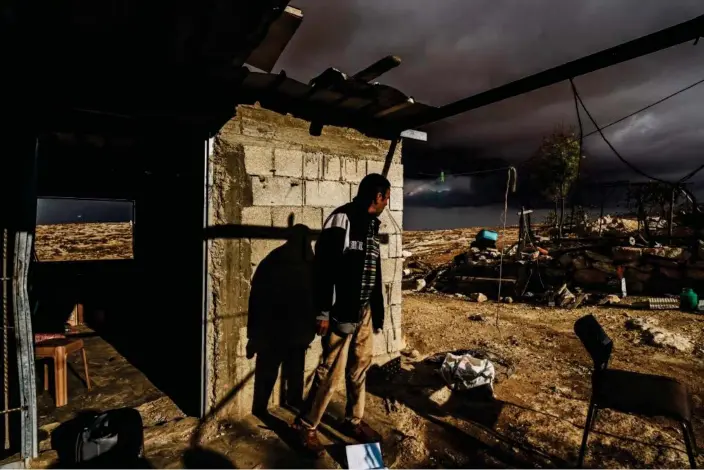  ?? Photograph: Marcus Yam/Los Angeles Times/Getty Images ?? A Palestinia­n man inspects the damage to his home and keeps an eye out for Israeli settlers, in Shaeb al-Botum, occupied West Bank, on 15 November 2023.