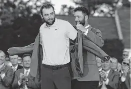  ?? JASON GETZ The Atlanta Journal-Constituti­on/TNS ?? Scottie Scheffler receives his green jacket on Sunday from 2023 Masters winner Jon Rahm. It was Scheffler’s second Masters victory in three years.