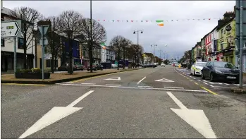  ??  ?? All going West: Flags and bunting provide only a thin disguise to the despair of a deserted Main Street in Castleisla­nd on the Covid-19 lock-down St. Patrick’s Day 2020.