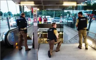  ?? LUKAS SCHULZE/DPA, TNS ?? Police officers stand watch at the Georg-Brauchle-Ring subway station during the massive manhunt Friday night.