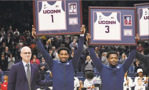  ?? Jessica Hill / Associated Press ?? UConn’s Christian Vital (1) and Alterique Gilbert (3) stand by coach Dan Hurley as they are honored on Senior Night before a game against Houston on Thursday in Storrs.