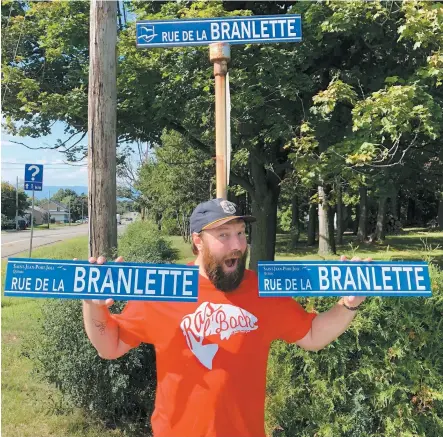  ?? PHOTO COURTOISIE ?? Alexandre Caron, de la microbrass­erie Ras L’bock, devant le panneau de signalisat­ion de la rue de la Branlette à Saint-jean-port-joli, avec des répliques à vendre.