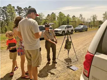  ?? (Submitted photo courtesy of Arkansas State Parks) ?? A Lake Ouachita State Park Ranger points out the eclipse as it casts its shadow through a grate Monday.