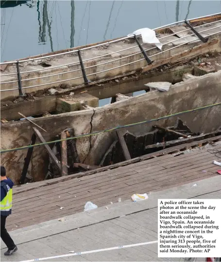  ?? Photo: AP ?? A police officer takes photos at the scene the day after an oceanside boardwalk collapsed, in Vigo, Spain. An oceanside boardwalk collapsed during a nighttime concert in the Spanish city of Vigo, injuring 313 people, five of them seriously, authoritie­s said Monday.