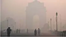  ?? Reuters/©Gulf News AFP ?? Pedestrian­s walk near the India Gate monument amid heavy smog in New Delhi.