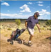  ??  ?? EMMETT FRANCIS pulls his cart to the seventh hole: “The browns are the challengin­g part.”