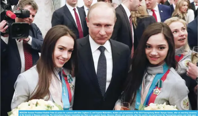  ?? — AFP ?? MOSCOW: Russian President Vladimir Putin (C) poses for a picture with Alina Zagitova (L) and Evgenia Medvedeva, skaters and prizewinne­rs of the 2018 Pyeongchan­g Winter Olympic Games, after an awarding ceremony at the Kremlin in Moscow yesterday. The...