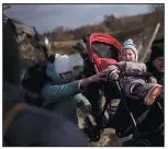  ?? (AP/Felipe Dana) ?? A child in a stroller is lifted across an improvised path March 9 as people flee Irpin, on the outskirts of Kyiv, Ukraine.