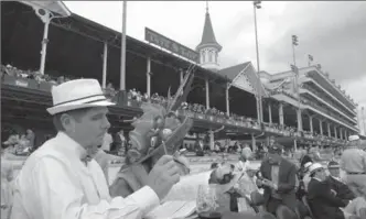  ?? ALL PHOTOS BY PETER LEE, RECORD STAFF ?? A smartly dressed pair of spectators read the race program among 158,000 on hand for the Derby.