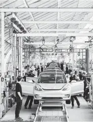  ?? Justin Kaneps / New York Times file ?? Workers assemble Tesla Model 3s at the company’s factory in Fremont, Calif.