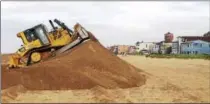  ?? AP PHOTO/MICHAEL R. BLOOD, FILE ?? In this 2015 file photo, a bulldozer piles sand into a high berm to protect homes along Sunset Beach in Huntington Beach, Calif. The state’s Ocean Protection Council decided weeks ago to update its sea-rise guidance for state and local government­s.