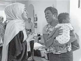  ?? Annie Mulligan ?? Aliyah Munshi, left, greets Andrea Williams and her 6-month-old son, Jackson, during Houston Open Mosque Day on Saturday in Katy.