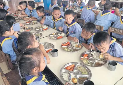  ??  ?? Youngsters tuck into a nutritious and hearty lunch prepared at a cost of 20 baht of state subsidy per student per day.