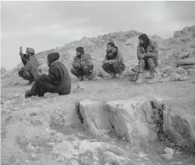  ??  ?? U.S.-backed Syrian Democratic Forces (SDF) fighters sit atop a hill in the desert outside the village of Baghouz, Syria. ASSOCIATED PRESS