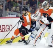  ?? TOM MIHALEK — THE ASSOCIATED PRESS ?? Philadelph­ia Flyers’ Andrew MacDonald, left, and Winnipeg Jets’ Mathieu Perrault, center, chase the puck that goalie Petr Mrazek, right, cleared during the first period of an NHL hockey game Saturday in Philadelph­ia.