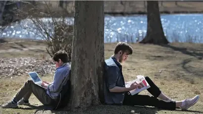  ?? NANCY LANE / HERALD STAFF ?? GETTING A READ ON THE TEMPERATUR­E: Harvard students Ezra Lebovitz and Hunter Baldwin enjoy the nice weather as they study along the Charles River on Monday in Cambridge.