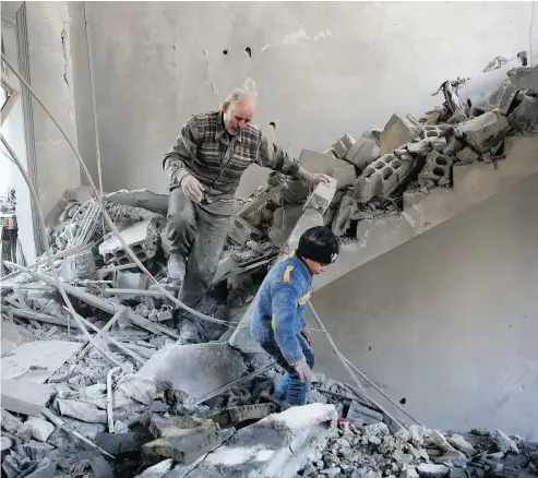  ?? AMER ALMOHIBANY / AFP / GETTY IMAGES ?? Abu Rabih, 65, and his eight-year- old grandson Yahya descend through the rubble following airstrikes by regime forces which hit the building where they live in the rebel-held Eastern Ghouta region on the outskirts of Damascus.