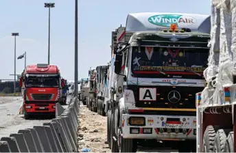  ?? — AFP photo ?? Egyptian trucks carrying humanitari­an aid bound for the Gaza Strip queue outside the Rafah border crossing on the Egyptian side.