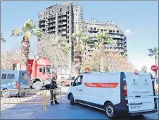  ?? — aFP photo ?? a police officer allows passage to a mortuary van at the multistore­y residentia­l block ravaged by a huge fire that killed at least nine people, in Valencia.