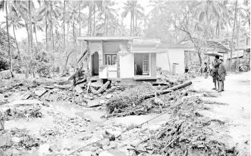  ?? — AFP photo ?? Indian people look at a house destroyed by a landslide at Kannapanak­undu village, about 422 km north of Trivandrum, in Kerala.