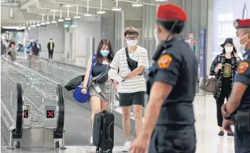  ?? PORNPROM SATRABHAYA ?? Officials and travellers wear face masks at Suvarnabhu­mi airport on Thursday.