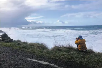  ?? Gillian Flaccus / Associated Press ?? A man photograph­s waves crashing onto the cliffs at Rodea Point in Lincoln County, Ore., during an extreme high tide event last month that coincided with a big winter storm.