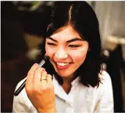  ??  ?? A stylist works on the make-up for Japanese model Rina Fukushi in back stage before a show by Japanese designer Tae Ashida.