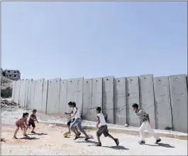  ?? PICTURE: AMMAR AWAD / REUTERS ?? WALL OF CONFLICT: Palestinia­n children play near a section of the controvers­ial Israeli wall along the West Bank. Fallout from President Donald Trump’s decision to move the US embassy to Jerusalem continues to grow.