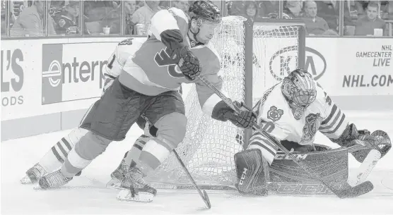  ?? | CHRIS SZAGOLA/AP ?? Flyers winger Michael Raffl tries awraparoun­d shot against Hawks goalie Corey Crawford in the second period.